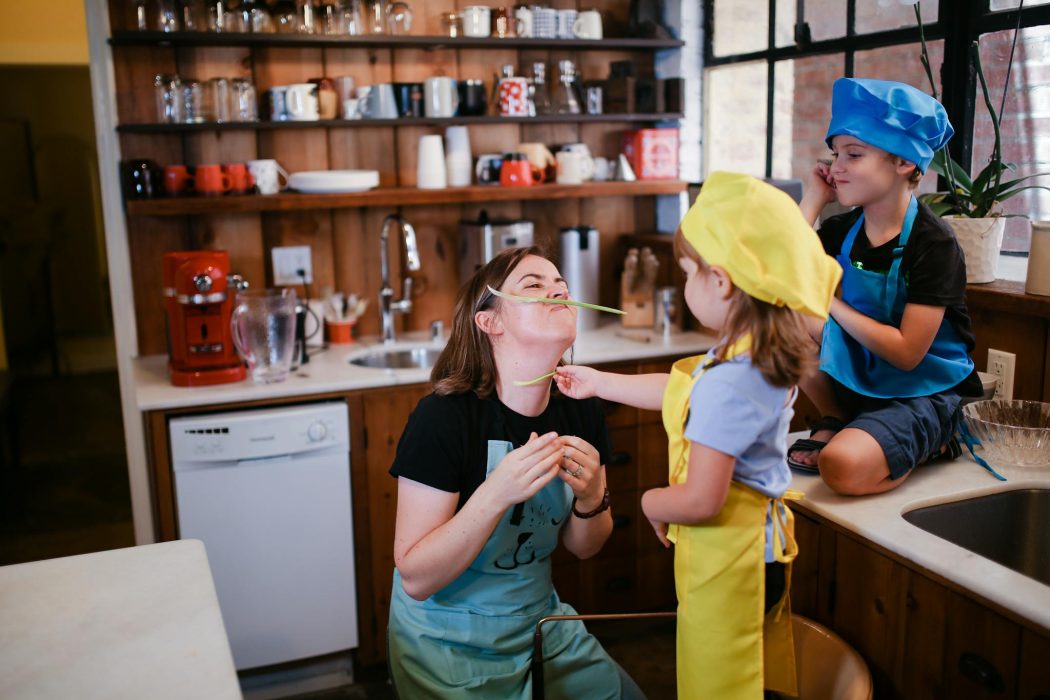 A mother and her children having fun in the kitchen with playful cooking activities.