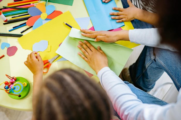 Kids crafting with colorful paper and materials in a creative classroom setting.